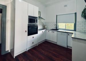 ダボにあるCharming home in Central Dubboの白いキャビネットとコンロ付きオーブンを備えたキッチン