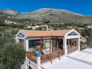 a house with a large deck with mountains in the background at Sea Rock Apartment in Ayia Evfimia