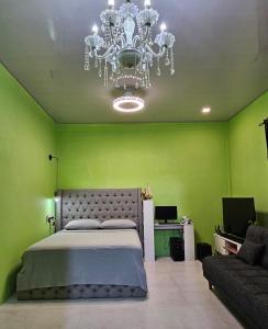a green bedroom with a large bed and a chandelier at Iruka Guesthouse in Faresmathoda