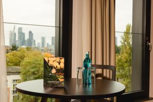 美因河畔法兰克福Rioca Frankfurt Posto 7的一张桌子,上面装有瓶子,还有一个袋子放在窗户上