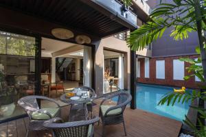 eine Terrasse mit Tisch und Stühlen neben einem Swimmingpool in der Unterkunft Casa 2565 by tisyastays in Anjuna