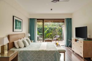 ein Schlafzimmer mit einem Bett mit Fernseher und einem Balkon in der Unterkunft Casa 2565 by tisyastays in Anjuna