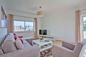 Una sala de estar con un sofá y dos sillas y un televisor. en Lagos Palm Tree 1 with Pool by Homing, en Lagos