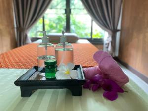 a tray with two bottles and flowers on a bed at Bang Po Hut in Ban Bang Po