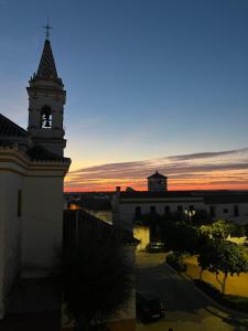 a building with a clock tower with a sunset in the background at Casa familiar pueblo in Valencina de la Concepción