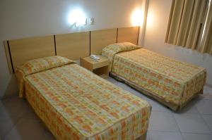 una habitación de hotel con dos camas en una habitación en SG Palace Hotel, en Taubaté 8 fotos más