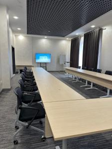 una sala de conferencias con una mesa grande y sillas en Almalyk Plaza Hotel, en Olmaliq