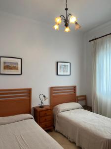 a bedroom with two beds and a chandelier at Casa familiar pueblo in Valencina de la Concepción