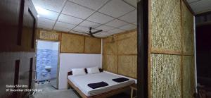 a small bedroom with a bed and a ceiling at Jungle Beach Resort in Neil Island