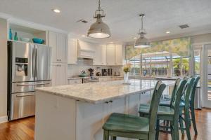 a kitchen with white cabinets and a large island with green chairs at The Crown House 4b Pool Home 6 mins to IR Beach in Largo