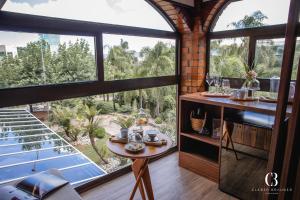 a room with a table and a large window at Casa Valduga Pousada Boutique in Bento Gonçalves