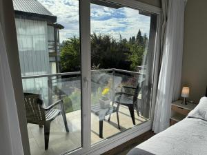 une chambre avec vue sur un balcon avec un lit et des chaises dans l'établissement Departamento Güemes, à San Carlos de Bariloche