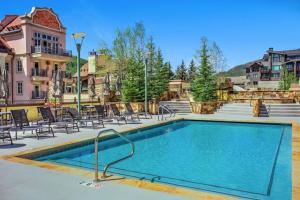 a swimming pool with chairs and a building at Luxury 2 Bedroom Lionshead Village Condo, Short Walk To Gondola in Vail