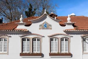 a white house with windows and a tiled roof at Casa da Estefânea in Sintra