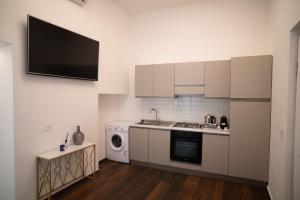 a kitchen with white cabinets and a tv on the wall at Enjoyhousebracciano Suite 3 in Bracciano
