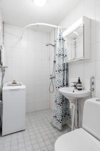 a white bathroom with a shower and a sink at Homelike Studio at the Very Center of Downtown Tampere in Tampella