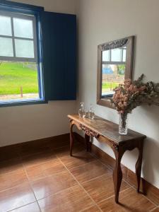 ein Zimmer mit einem Tisch mit einem Spiegel und einer Vase mit Blumen in der Unterkunft Casa no Chafariz in Tiradentes