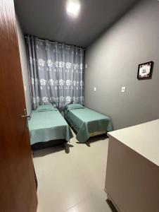 ein kleines Zimmer mit zwei Betten und einem Fenster in der Unterkunft Casa para família em Bombinhas in Bombinhas