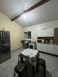 a kitchen with a table and chairs and a refrigerator at Casa para aluguel de temporada em Caraguatatuba, ao lado de São Sebastião in Caraguatatuba