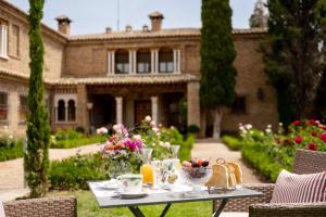 a table in front of a large house with flowers at Cigarral del Carmen in Toledo