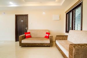a room with a couch and a chair with red pillows at Super Capital O RR Towers by CJ in Vijayawāda