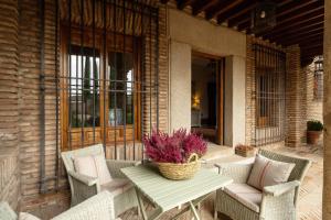 a patio with chairs and a table with a basket of flowers at Cigarral del Carmen in Toledo