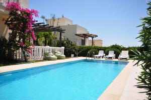 a swimming pool with two lawn chairs and a fence at Villa Romantica 17 in Milas