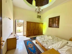 a bedroom with a bed and a desk and a chandelier at Sunset Haven Guesthouse in Luxor