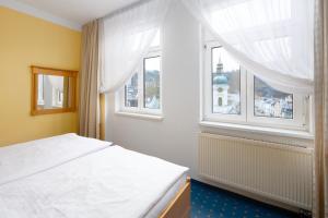 a bedroom with a white bed and a window at Wellness Hotel Jean De Carro in Karlovy Vary
