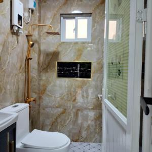 a bathroom with a toilet and a shower and a window at Family Suite 4-6 Pax GLENMARK'S Homestay near the beach in Pagudpud