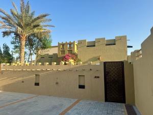 a building with a gate and a palm tree at 2 Bedroom Villa in Ras Al Khaimah with Privat swimming Pool in Ras al Khaimah