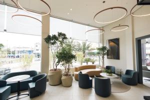 a lobby with tables and chairs and plants at Art Hotel in Tubarão