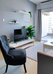 a living room with a black chair and a tv at Cornelius Cosy Apartments in Caesar Resort & SPA in Perivolia tou Trikomou