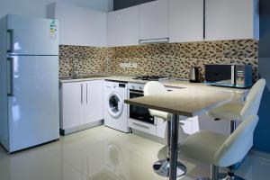 a kitchen with a refrigerator and a table with chairs at Cornelius Cosy Apartments in Caesar Resort & SPA in Perivolia tou Trikomou
