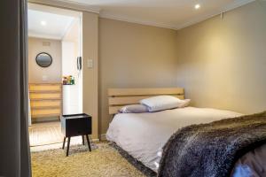 a bedroom with a bed and a dresser at Cozy Cottage in Constantia in Cape Town