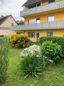 a yellow house with bushes and flowers in a yard at Ferienhaus am Geiersberg in Walkenried
