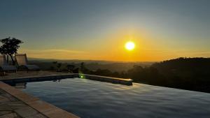 a swimming pool with a sunset in the background at Casa Mediterrânea no alto da montanha in Itu +2 photos