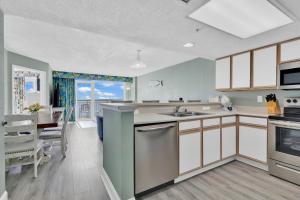a kitchen with white cabinets and a table and a dining room at Baywatch Resort Oceanfront Dream Maker in Myrtle Beach +41 photos