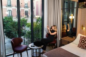Eine Frau, die in einem Hotelzimmer sitzt und aus dem Fenster schaut. in der Unterkunft Room Mate Leo, Granada in Granada