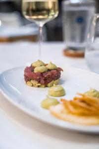 a plate of food on a table with a glass of wine at Palmares Beach House Hotel - Adults Only in Lagos