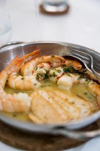 a plate of shrimp with a fork in a pan at Palmares Beach House Hotel - Adults Only in Lagos