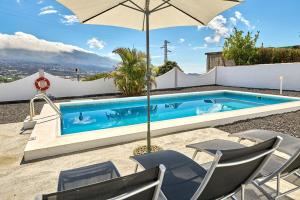 una piscina con sillas y sombrilla en Elisa, en El Paso