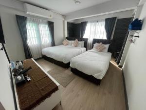 a hotel room with two beds and a desk at Charma Home Watket in Chiang Mai