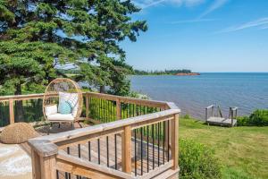 a wicker chair sitting on a deck overlooking the water at Waterfront Cottage beach access in Stratford