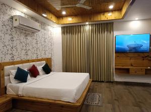 a bedroom with a bed and a tv on the wall at The Crown in Dharamshala