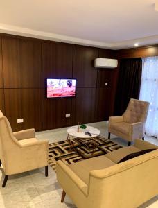 a living room with a couch and chairs and a tv at Grand Palmac Hotel in Abuja