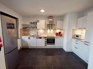 a kitchen with white cabinets and a brown tile floor at Großzügige Monteurwohnungen mit perfekter Verkehrsanbindung und Parkplatz in Lampertheim