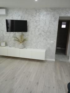 ein weißes Wohnzimmer mit einem TV an der Wand in der Unterkunft Apartament Ultimul Leu in Galaţi