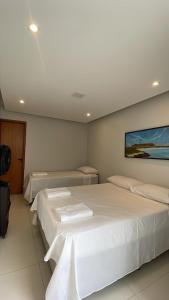 a bedroom with two beds and a painting on the wall at Pousada Suites Phison in Cabo Frio