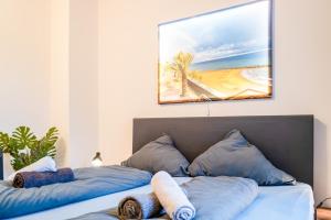 a bed with blue pillows and a painting on the wall at #221 Moderne City Wohnung im Herzen von Neuss in Neuss